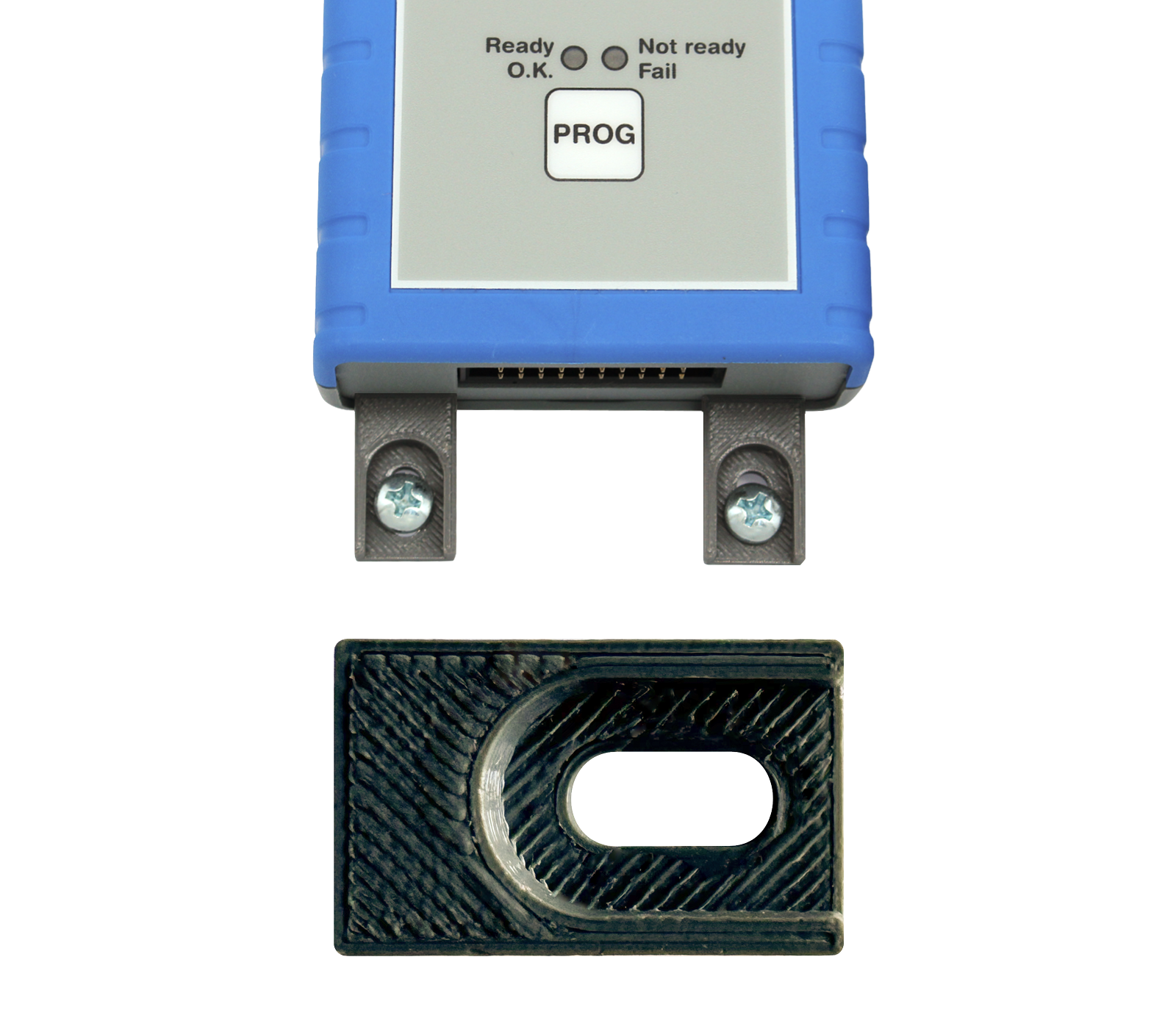 Image depicts a small electronic device with a blue casing featuring indicator lights labeled "Ready," "Not Ready," and "Fail," along with a button labeled "PROG." Below, there is a black connector piece with an oval cutout, likely for attachment or interface purposes.